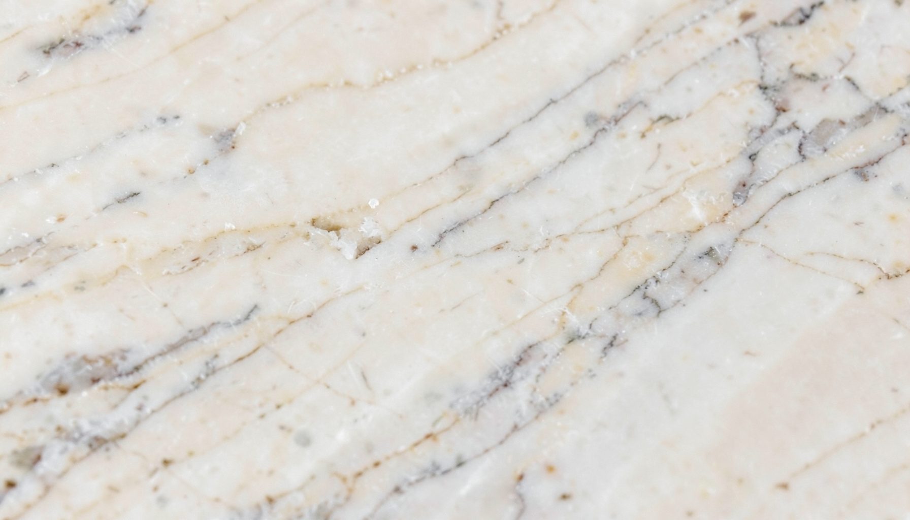A close-up of textured marble surface in soft cream and grey veins, calm and elegant mood