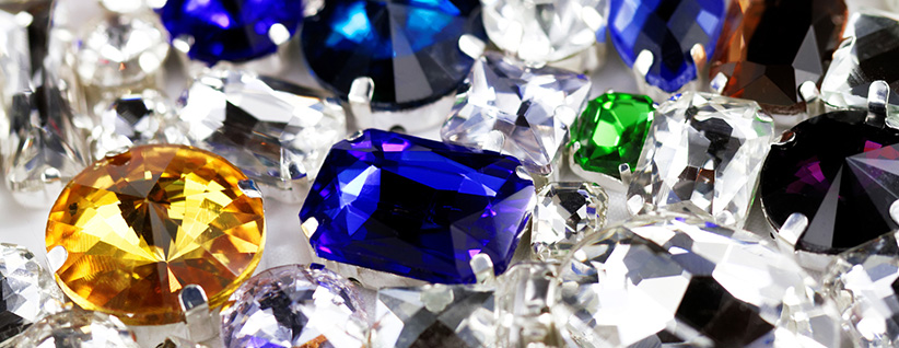 Close-up of multicolored faceted gemstones in blue, yellow, green and clear tones, vibrant and sparkling