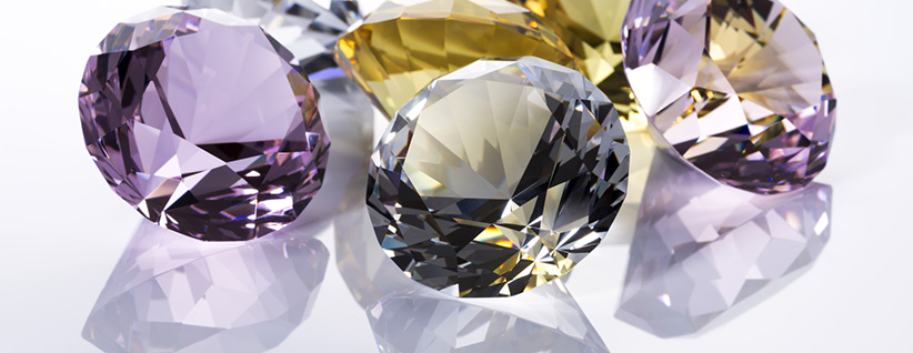 Cluster of faceted gemstones in purple and yellow tones reflecting light, elegant and sparkling