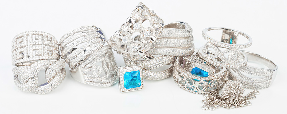 Collection of silver rings and bracelets with sparkling gemstones on a white background, luxurious and elegant